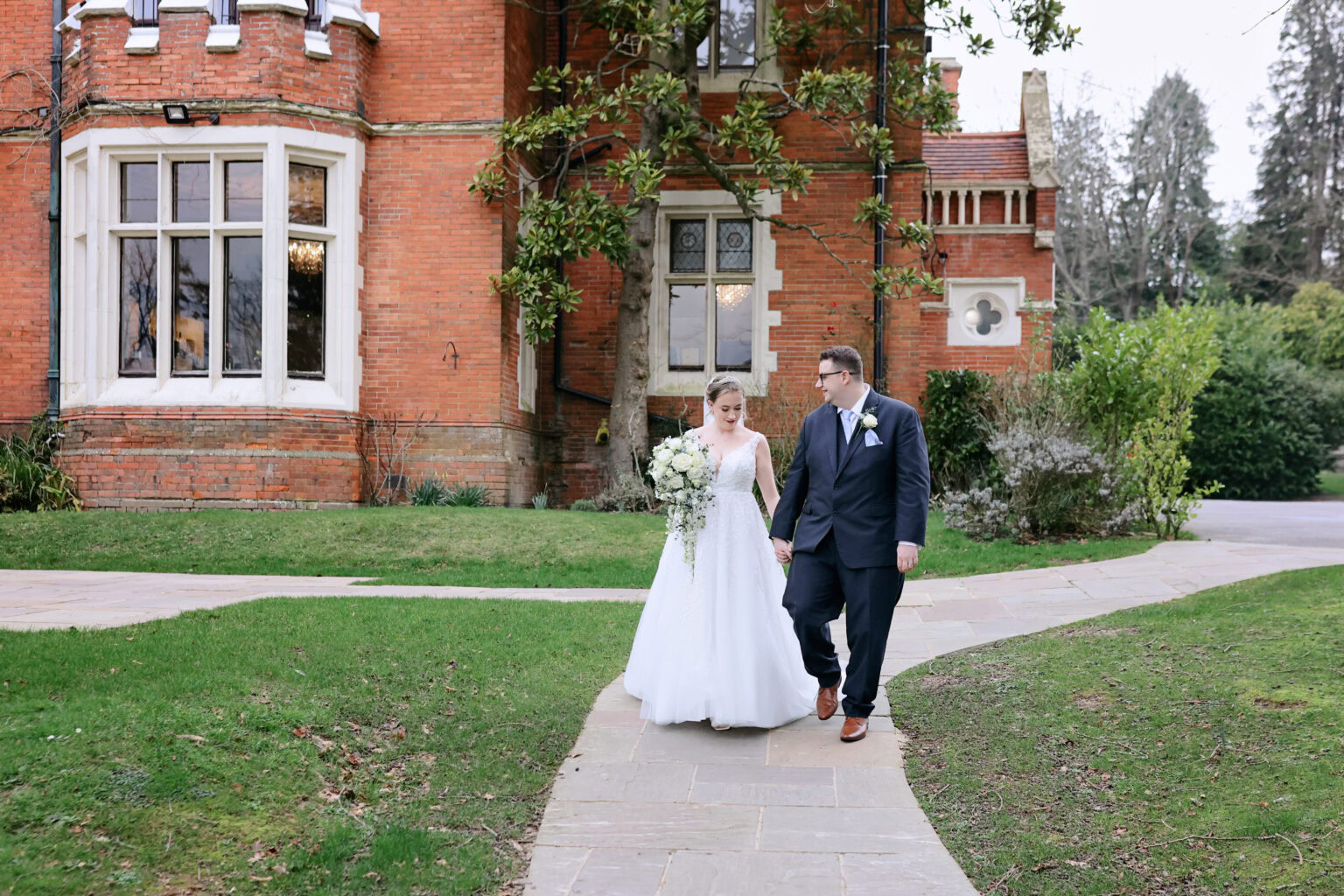 Bride and groom walking through the grounds of Highley Manor in February