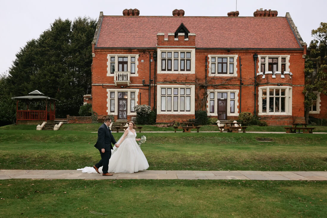 Bride and groom walking through the grounds of Highley Manor in February